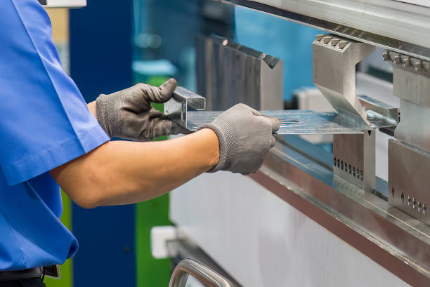 Close up the bending machine operator hold the sheet metal parts and  wear safety  glove. The sheet metal working operation by skill operator.